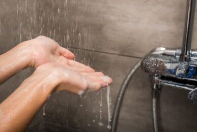 Shower Plumbing Issues: Two hands in the shower water