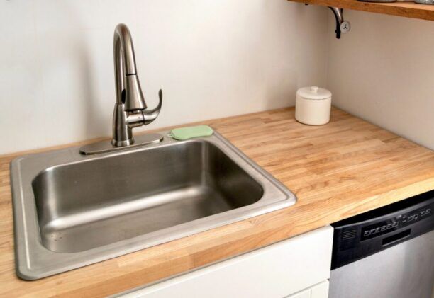 Stainless steel kitchen sink with modern faucet installed in a wooden countertop.