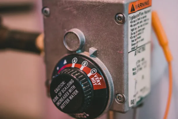 Plumber adjusting a home water heater temperature for safety and efficiency.